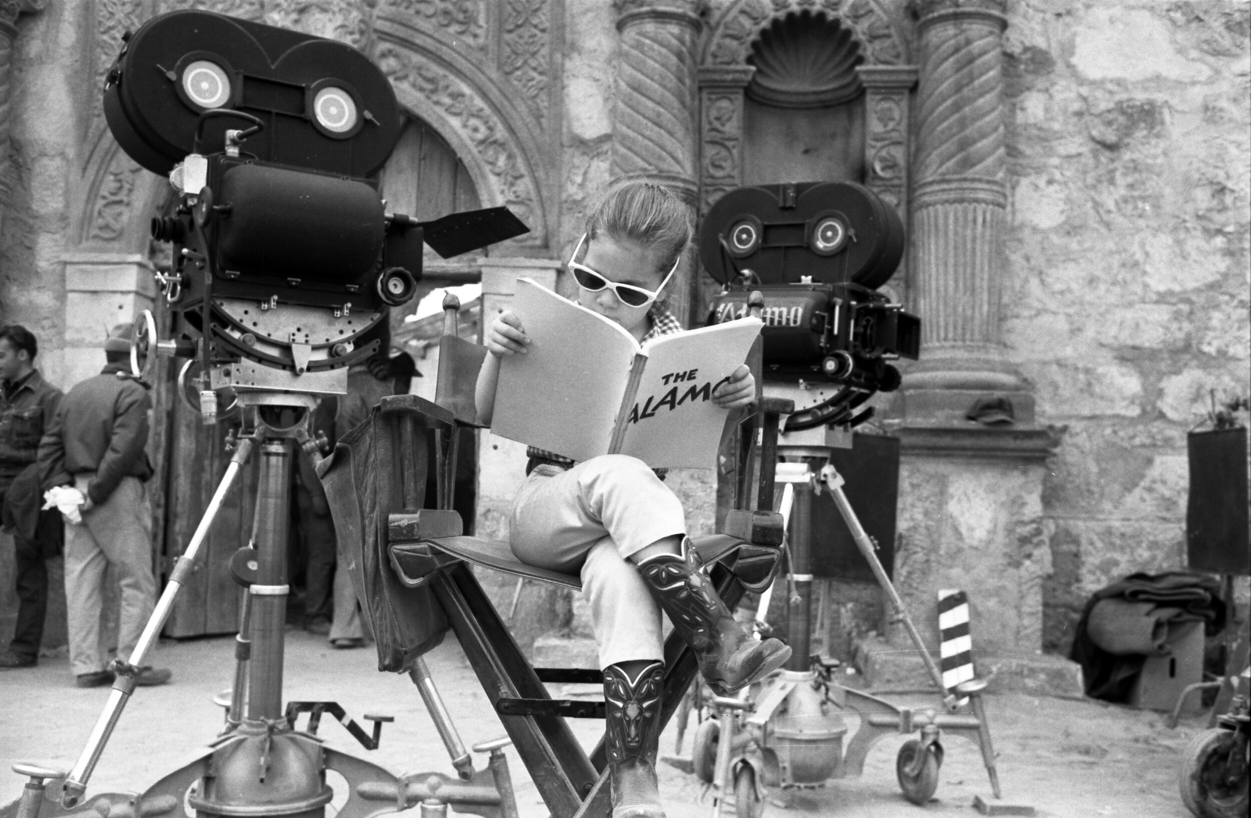 Aissa in the director’s chair reading her dad’s script on set of The Alamo (1960).