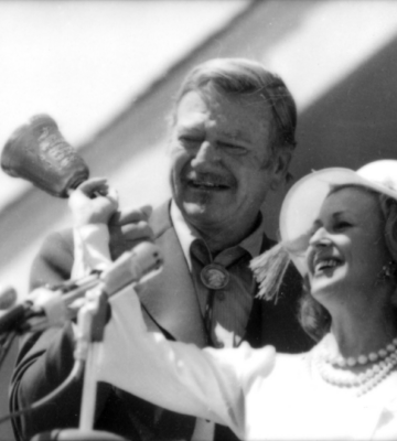 John Wayne and Marylou Whitney take part in Cody’s “Let Freedom Ring” ceremony on July 4, 1976, celebrating America’s Bicentennial. Wayne rang one of four commemorative hand bells cast from material left over from repairs to the original Liberty Bell, marking one of the day’s most symbolic moments. (Courtesy of the Buffalo Bill Center of the West, Cody, Wyoming, USA; McCracken Research Library)